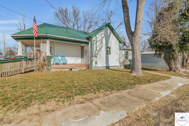 view of front of property with covered porch, metal roof, and a front yard