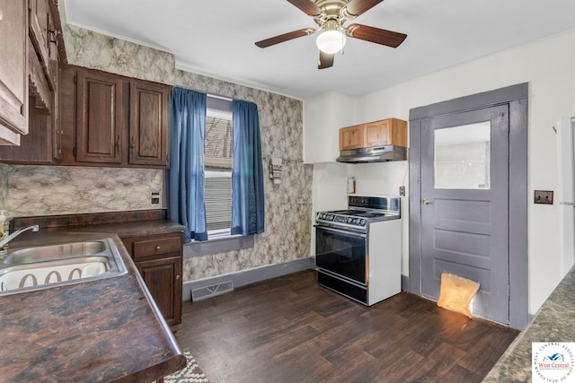 kitchen with under cabinet range hood, dark countertops, a sink, and stainless steel electric stove