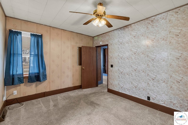 spare room with carpet floors, a ceiling fan, baseboards, and wallpapered walls