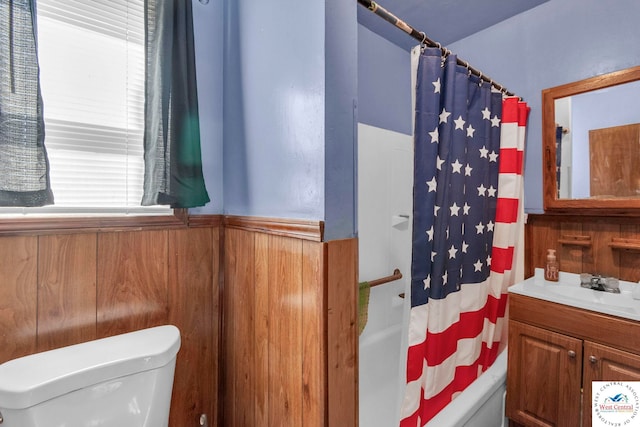 bathroom with a wainscoted wall, shower / bath combination with curtain, toilet, wood walls, and vanity