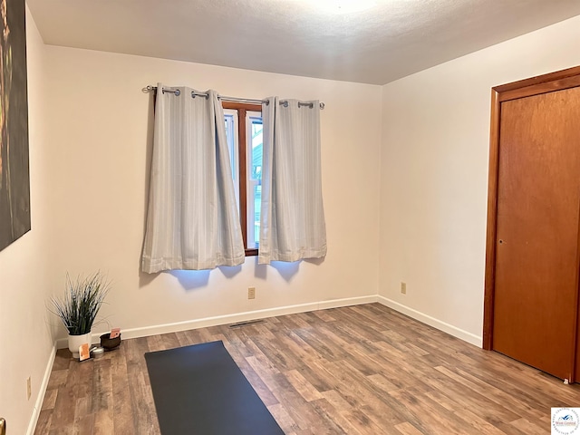 workout area with visible vents, baseboards, and wood finished floors