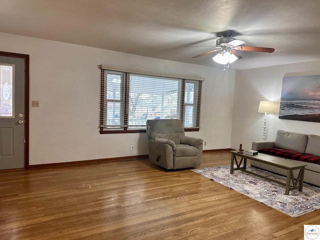 living area with ceiling fan, baseboards, and wood finished floors