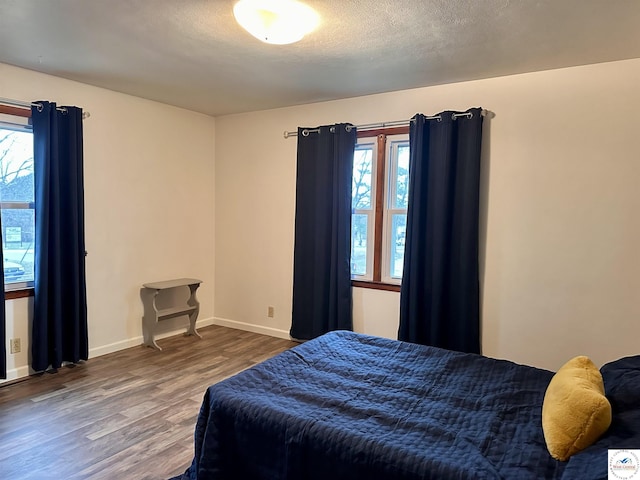 bedroom featuring dark wood-style flooring, multiple windows, a textured ceiling, and baseboards