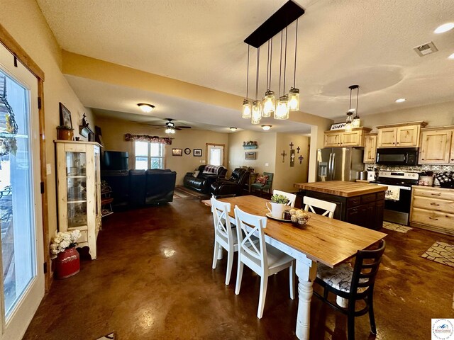 dining room featuring a ceiling fan, visible vents, finished concrete flooring, and a textured ceiling