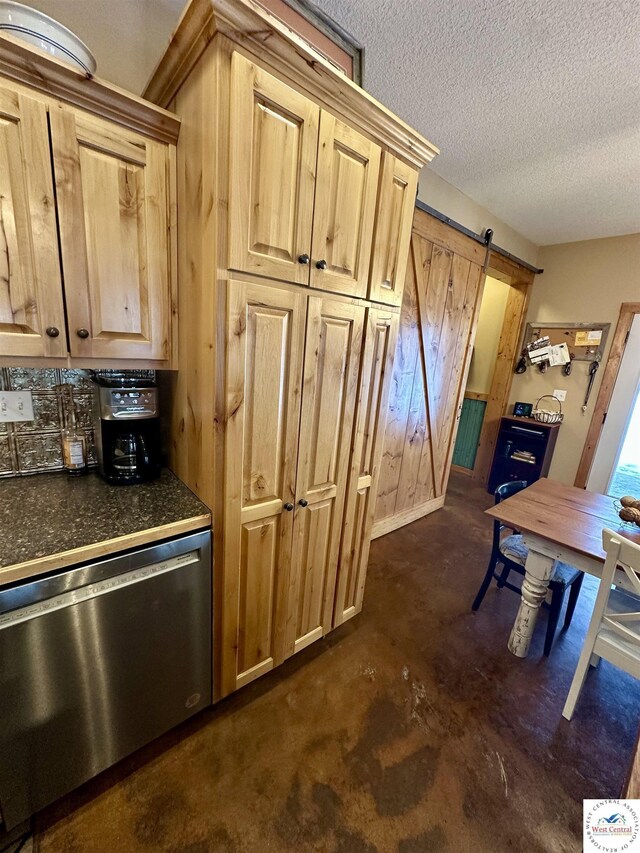 kitchen featuring a barn door, dark countertops, a textured ceiling, light brown cabinetry, and stainless steel dishwasher