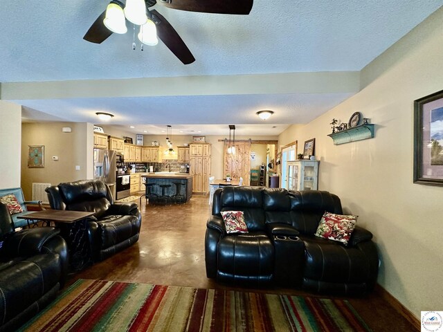 living area featuring finished concrete floors, baseboards, and a textured ceiling