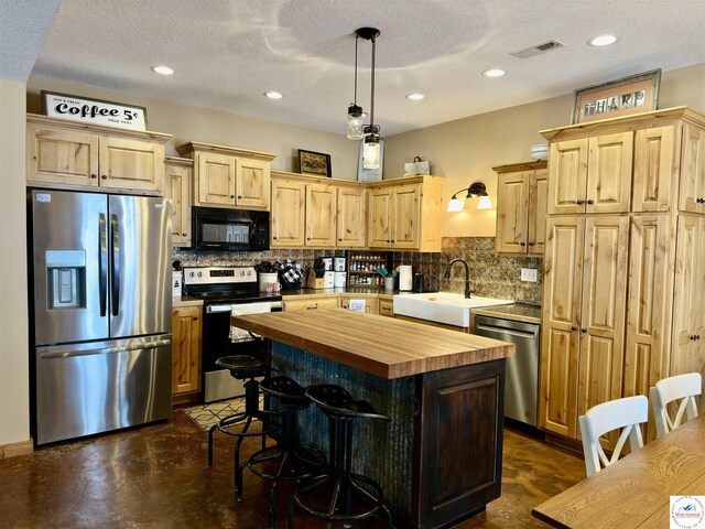 kitchen with concrete flooring, light brown cabinets, stainless steel appliances, a sink, and wood counters