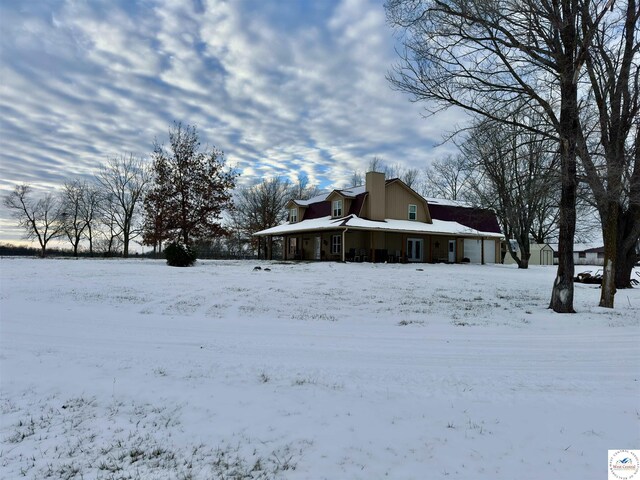 view of snowy exterior featuring a detached garage