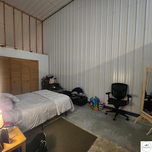 bedroom featuring concrete floors and metal wall