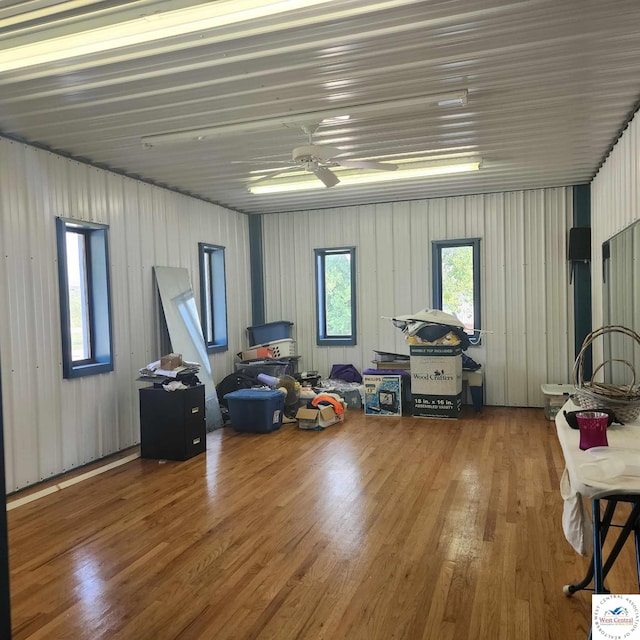 miscellaneous room featuring metal wall, a ceiling fan, and wood finished floors