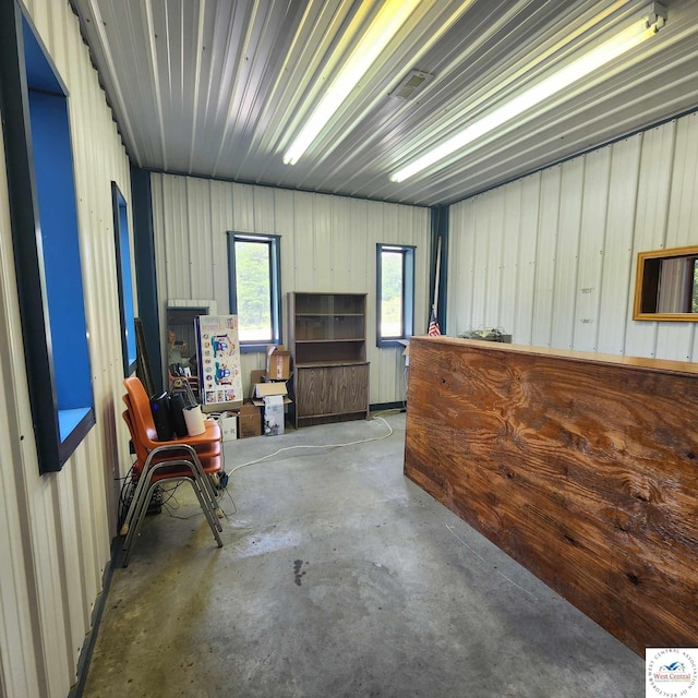 miscellaneous room featuring metal wall and unfinished concrete floors