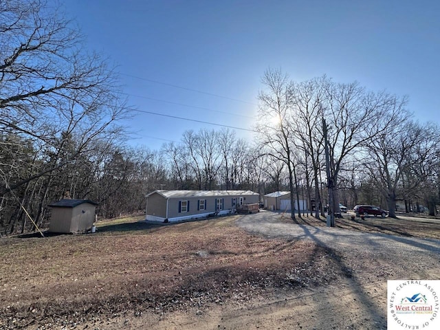 view of front of house featuring a shed, an outdoor structure, and dirt driveway