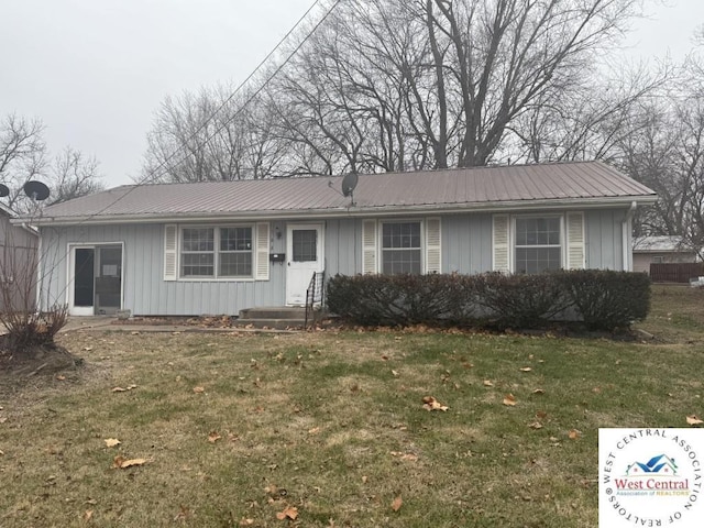 single story home featuring metal roof, board and batten siding, and a front yard