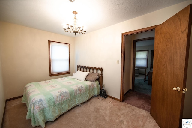 bedroom with a chandelier, light carpet, a textured ceiling, and baseboards