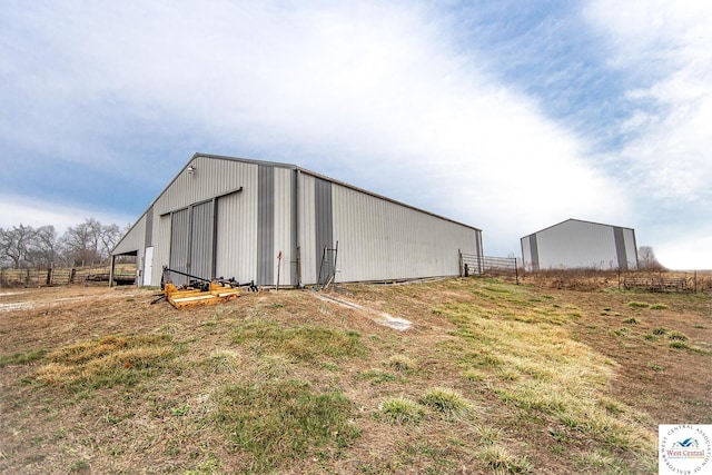 view of pole building featuring a rural view, fence, and a yard