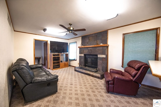 carpeted living area with ornamental molding, a tile fireplace, and ceiling fan