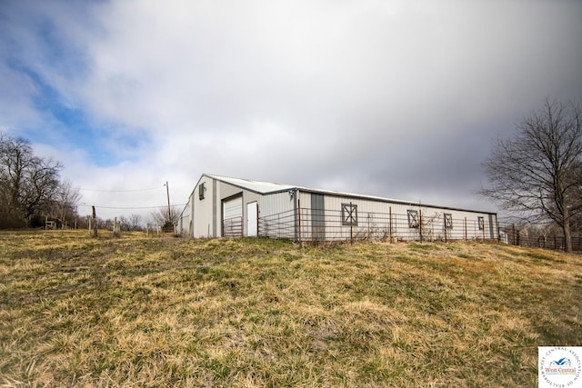 view of pole building with a lawn and fence