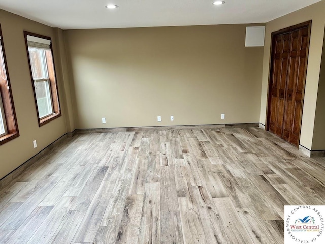 empty room featuring light wood-type flooring, baseboards, and recessed lighting