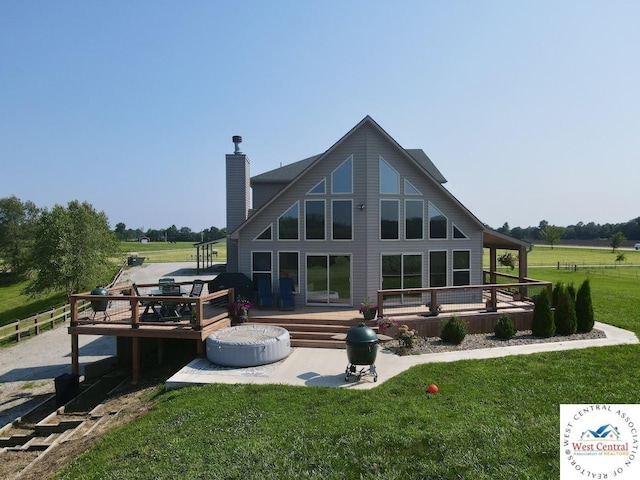 back of property with a rural view, a yard, a chimney, and a wooden deck