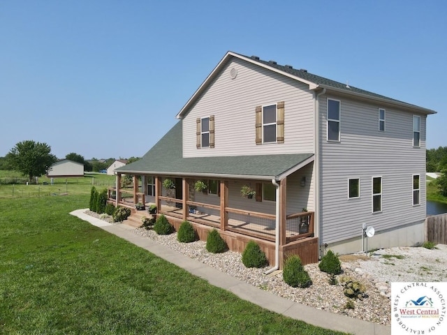 rear view of property with covered porch and a lawn