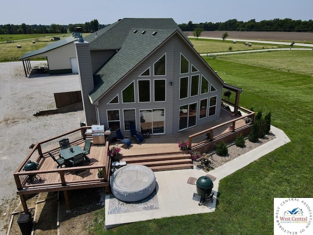 rear view of property featuring roof with shingles, a rural view, and a wooden deck