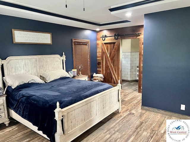 bedroom with wood finished floors and a barn door