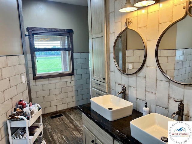 bathroom with wood finished floors, a sink, and tile walls