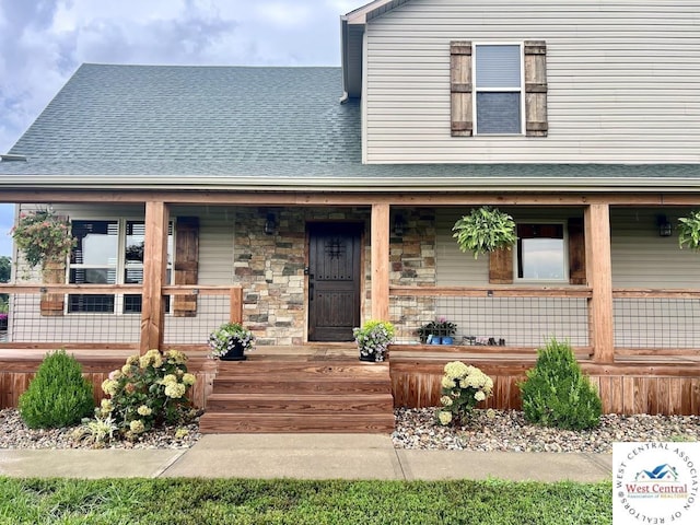 view of front of home with stone siding, a shingled roof, and covered porch