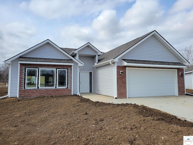 ranch-style house with concrete driveway, brick siding, an attached garage, and roof with shingles