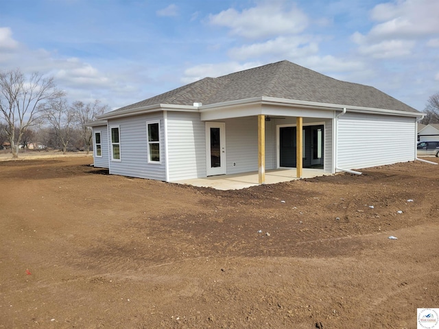 rear view of house with roof with shingles and a patio