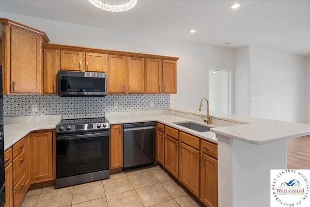 kitchen with a sink, stainless steel appliances, a peninsula, and brown cabinetry