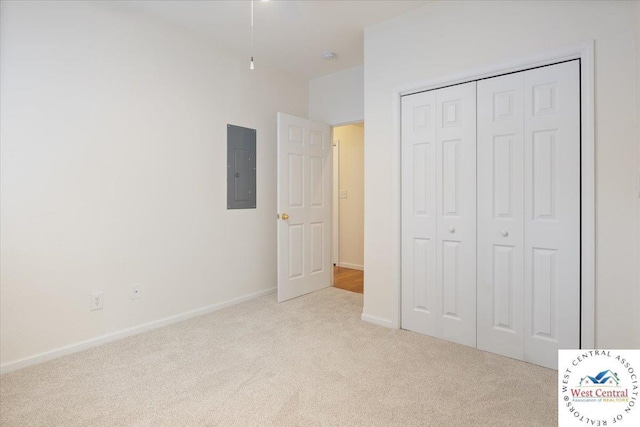 unfurnished bedroom featuring electric panel, baseboards, a closet, and carpet floors