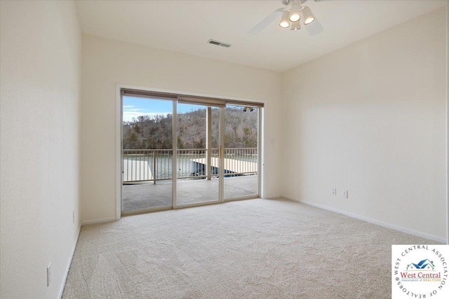 carpeted spare room with baseboards, visible vents, and ceiling fan