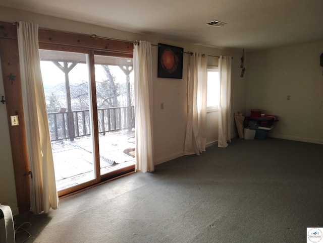 doorway to outside featuring carpet, visible vents, and a healthy amount of sunlight