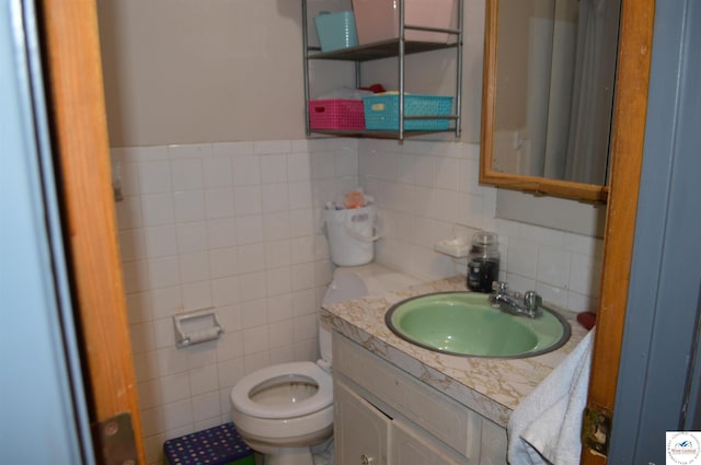 bathroom with toilet, tile walls, and vanity