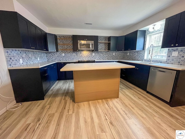 kitchen featuring appliances with stainless steel finishes, light countertops, open shelves, and a sink