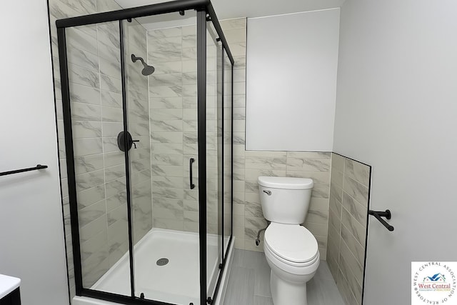 full bathroom with toilet, a stall shower, and tile walls