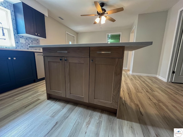 kitchen with blue cabinetry, ceiling fan, light wood-type flooring, and backsplash