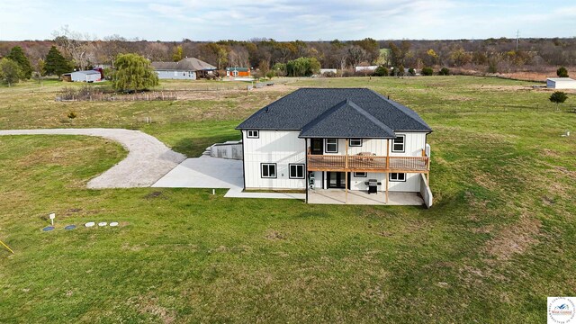 17788 Main Rd, Sedalia, MO 65301 - rear view of house with a patio area, a wooden deck, a lawn, board and batten siding, and a shingled roof