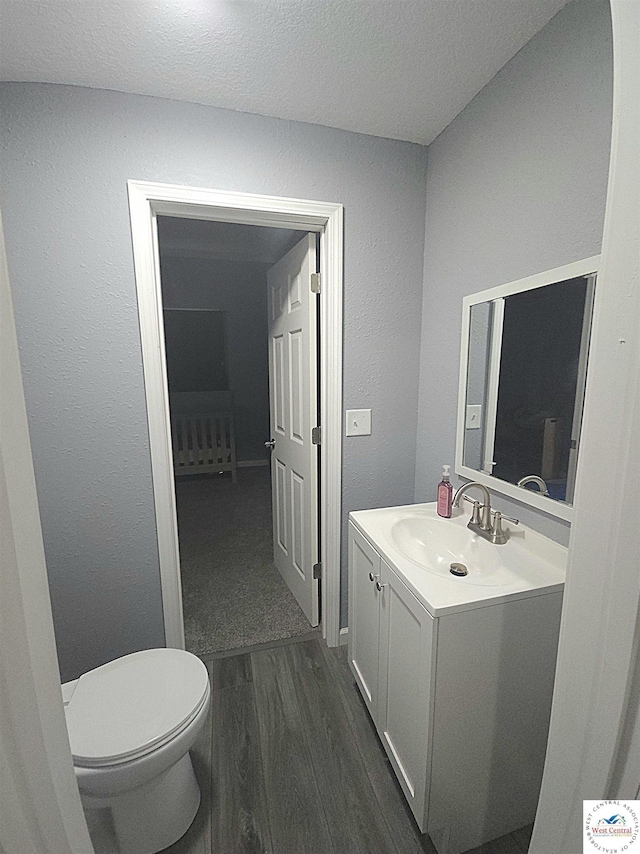 1012 E 7th St, Sedalia, MO 65301 - bathroom with vanity, wood finished floors, toilet, a textured wall, and a textured ceiling
