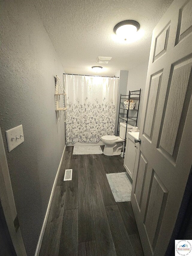 1012 E 7th St, Sedalia, MO 65301 - full bath with toilet, a textured ceiling, wood finished floors, baseboards, and vanity