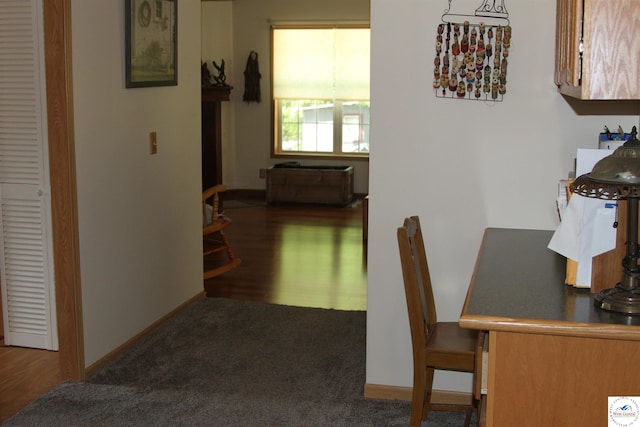 hall featuring baseboards, wood finished floors, and carpet