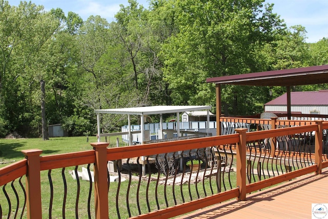wooden terrace featuring a storage shed, an outdoor structure, and a lawn