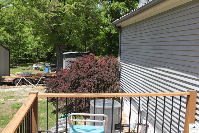 wooden terrace featuring a shed, central air condition unit, and an outbuilding