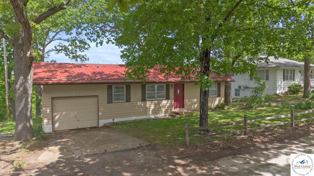 view of front of property featuring metal roof, driveway, a garage, and fence