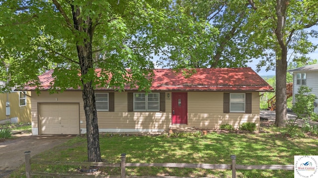 view of front facade with a front yard, driveway, an attached garage, and fence