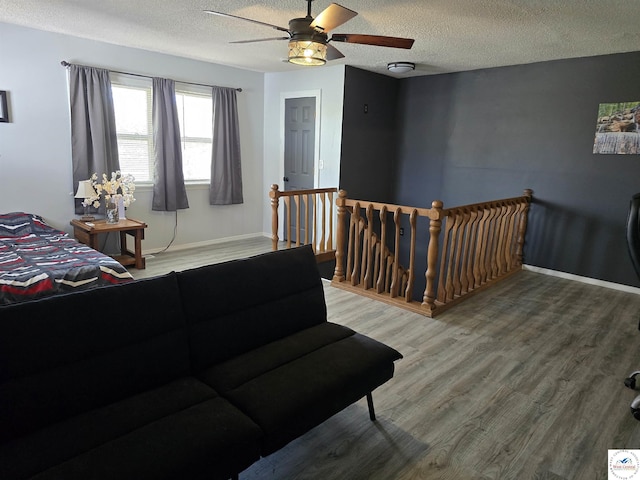 bedroom featuring a textured ceiling, ceiling fan, baseboards, and wood finished floors