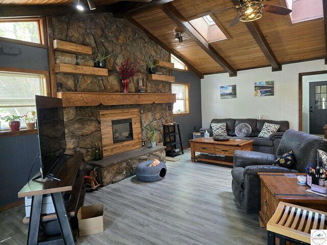 living area with a healthy amount of sunlight, a ceiling fan, wood finished floors, wooden ceiling, and lofted ceiling with skylight