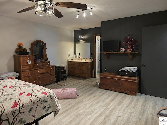 bedroom with rail lighting, ensuite bath, ceiling fan, and light wood-style floors