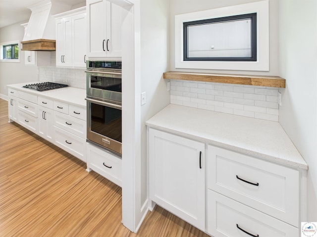 1248 Rich Blvd, Warrensburg, MO 64093 - kitchen with appliances with stainless steel finishes, light wood-style floors, backsplash, and custom exhaust hood